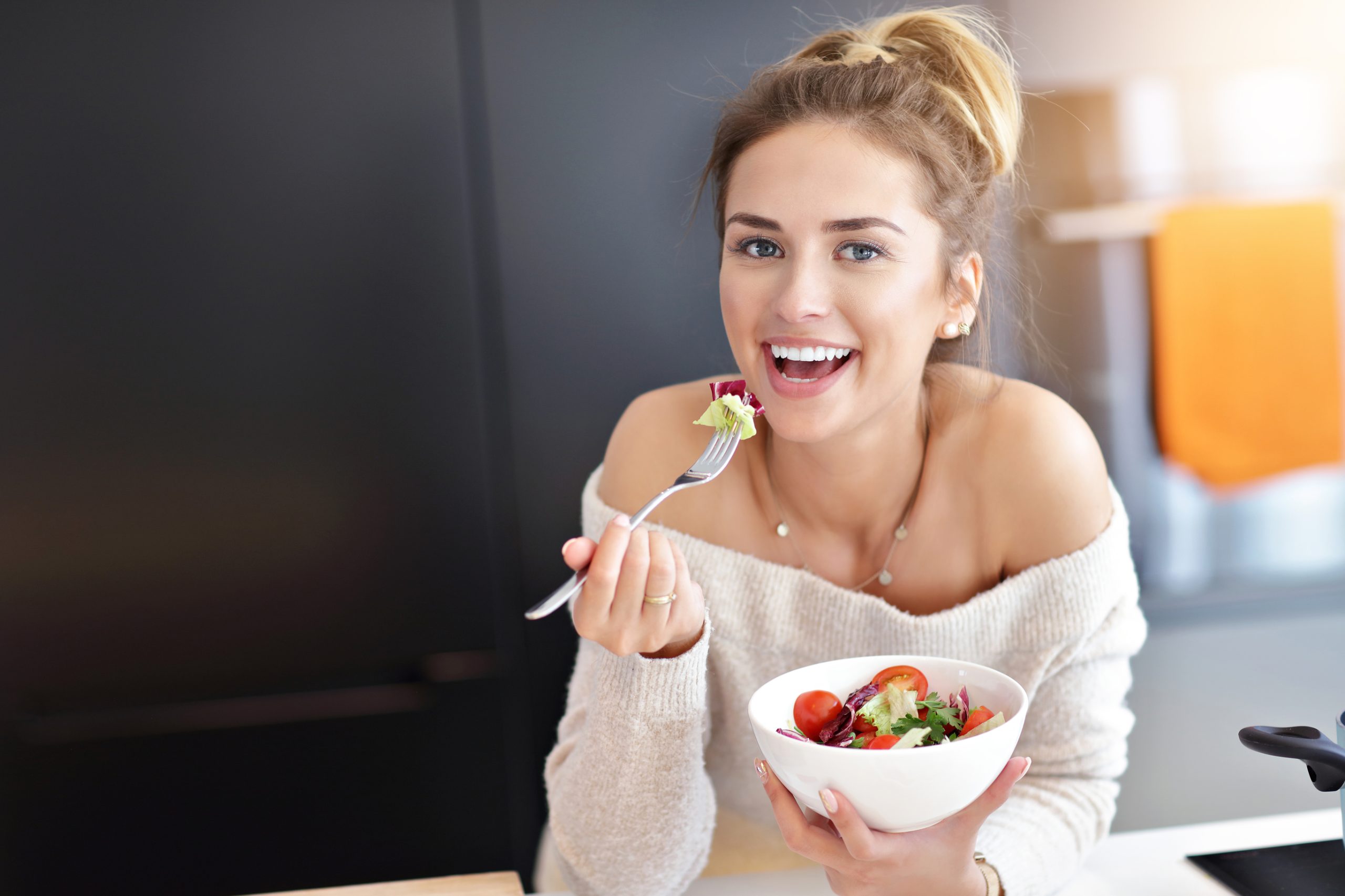 Young woman eating a vegetarian salad to acquire a six pack