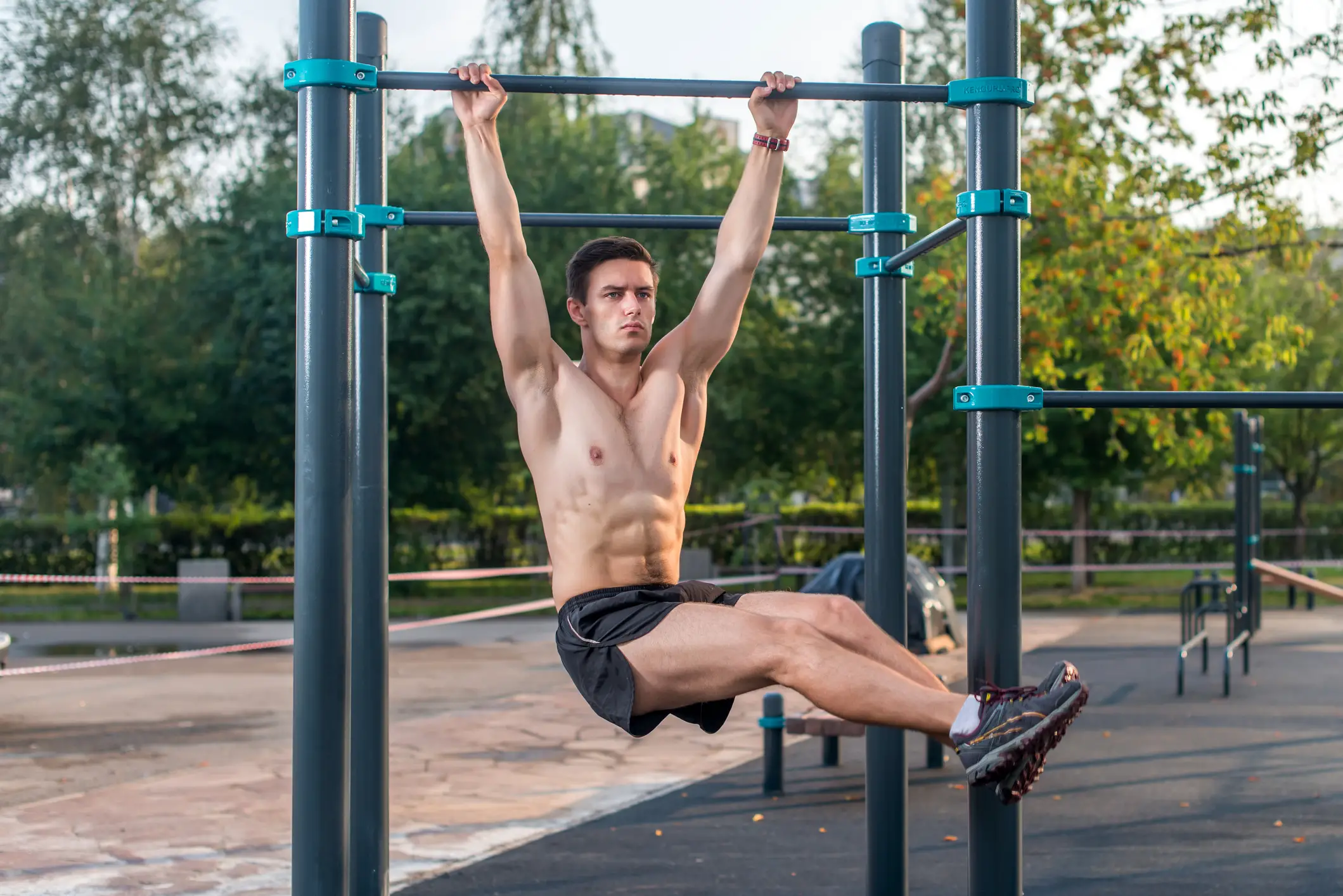 Athlete hanging on fitness station performing legs raises