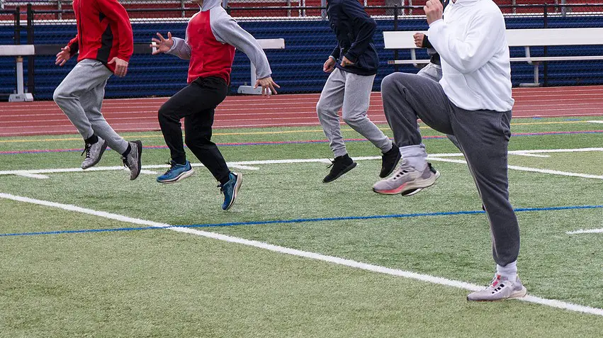 Boys On A High School Track Team Doing High Knees Running Drill