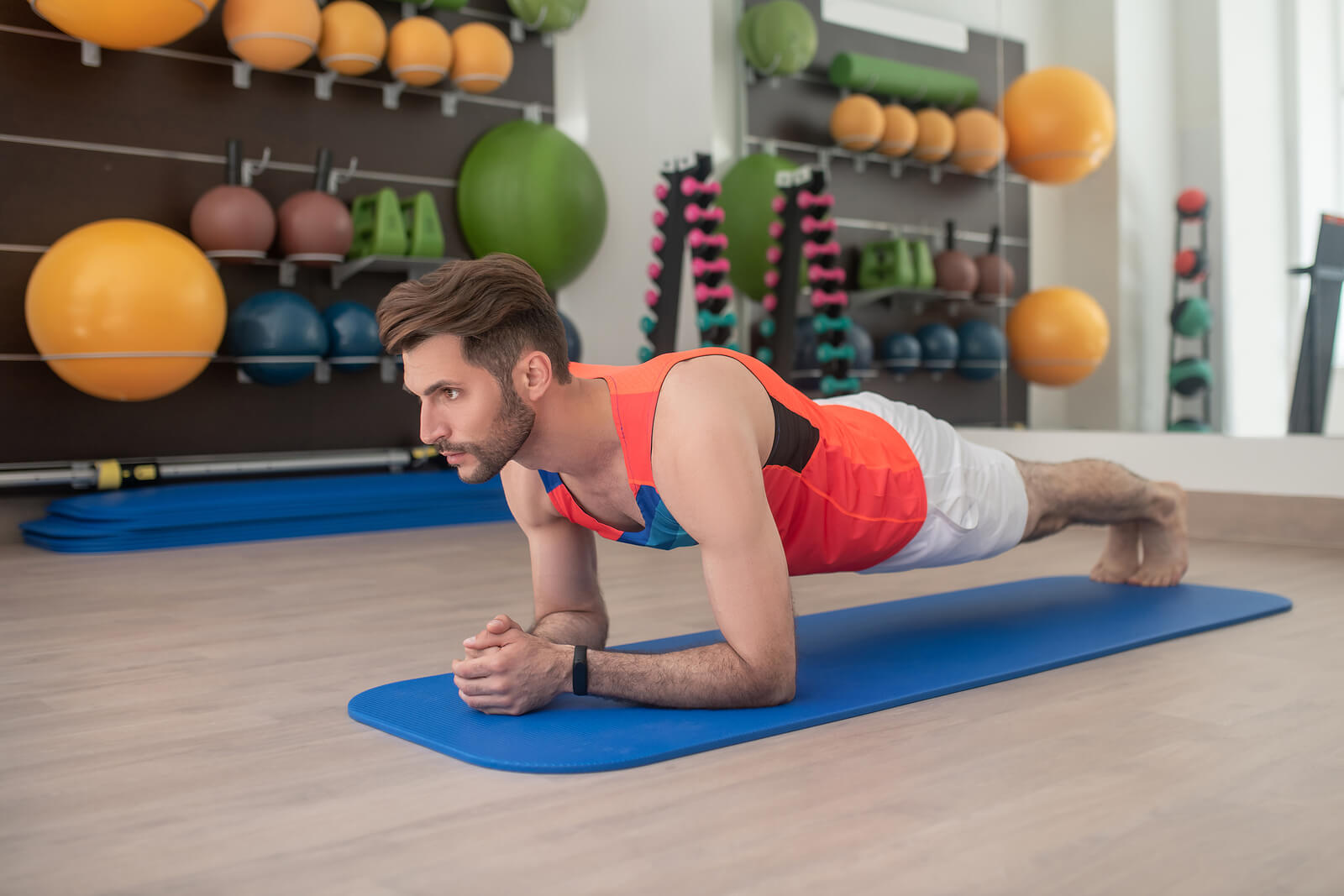 Bearded Young Male Standing In Dolphin Plank In The Gym