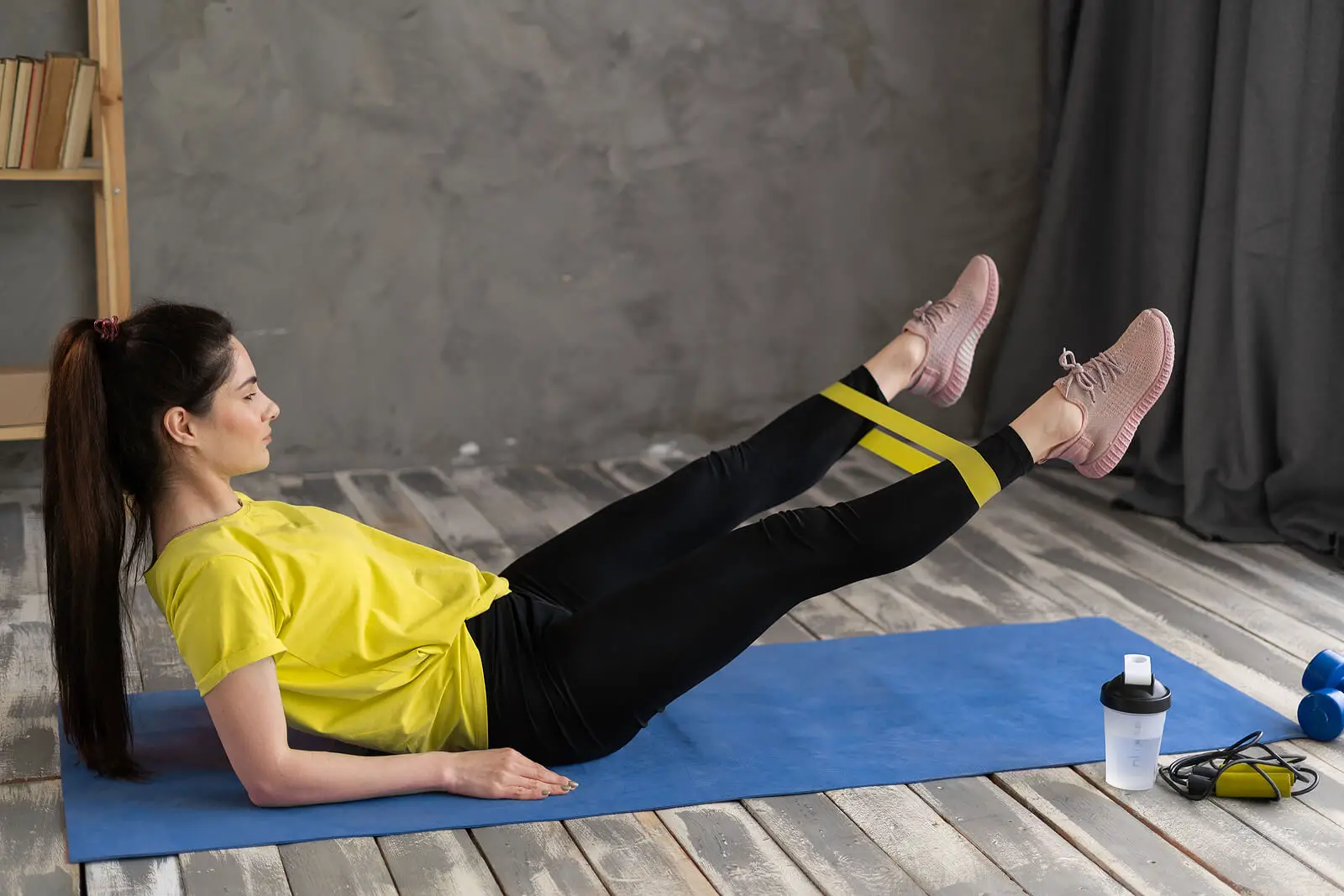 Happy Woman Exercising With Resistance Band Lying On Mat At Home