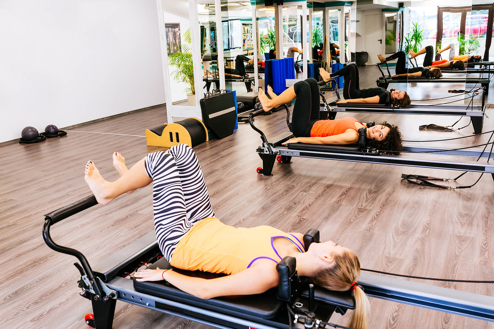 Women exercising on pilates reformer beds pose